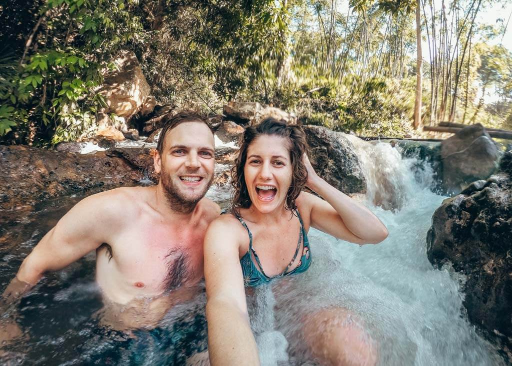 Two people sitting in a stream of water in Bajawa, Flores