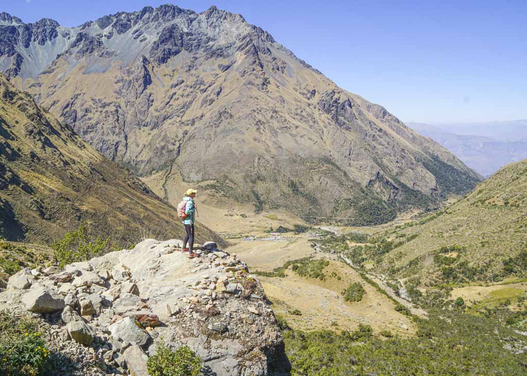 A girl standing on a ledge overlooking a beautiful valley