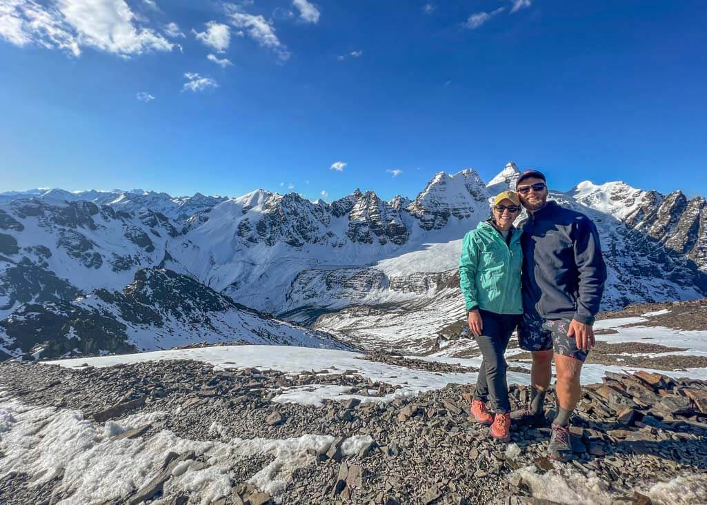 Two people standing on top of Pico Austria with Cordillera Real Mountain Range in the background