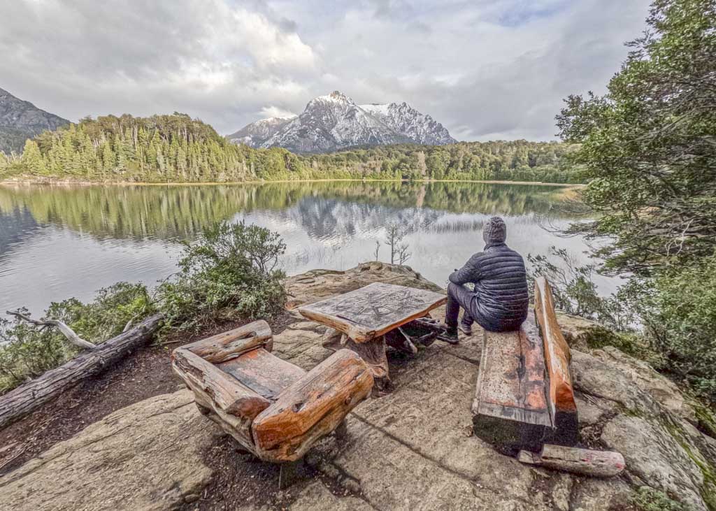 A man sitting on a bench overlooking a lake at one of the most beautiful places in Patagonia
