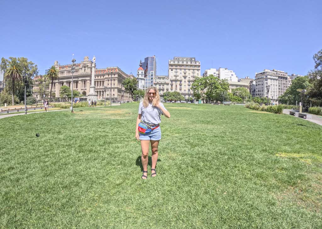 a girl standing on grass in front of buildings in Argentina