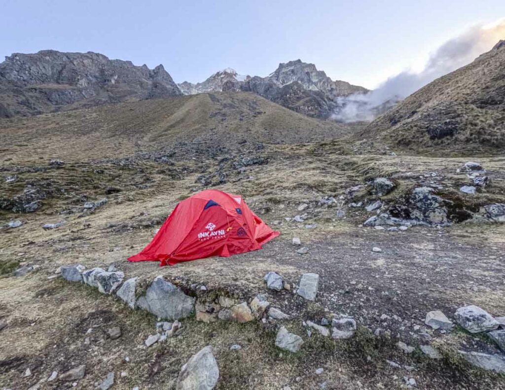 A red tent perched on the side of a mountain during the Salkantay trek and Inca Trail