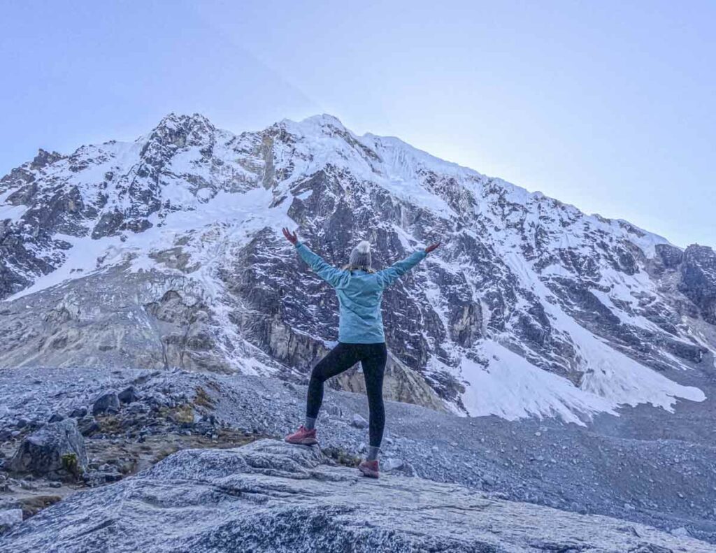 Carryn standing in front of Salkantay mountain with her hands in the air